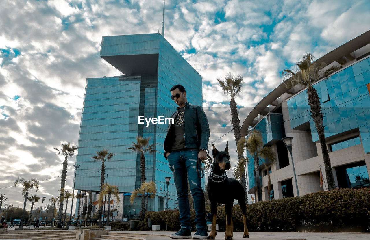 Man with dog standing against buildings in city