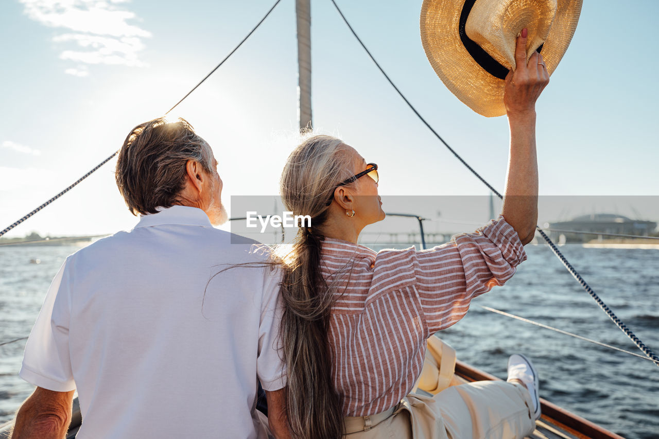 Rear view of women sailing on boat in sea against sky