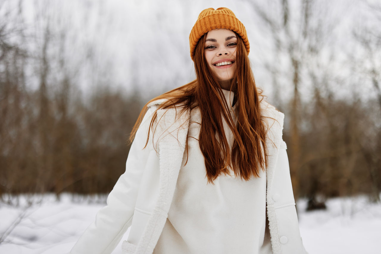 young woman standing on snow covered field during winter