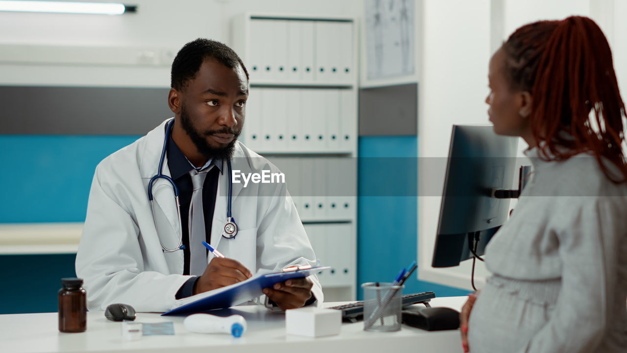 Pregnant woman consulting doctor at clinic