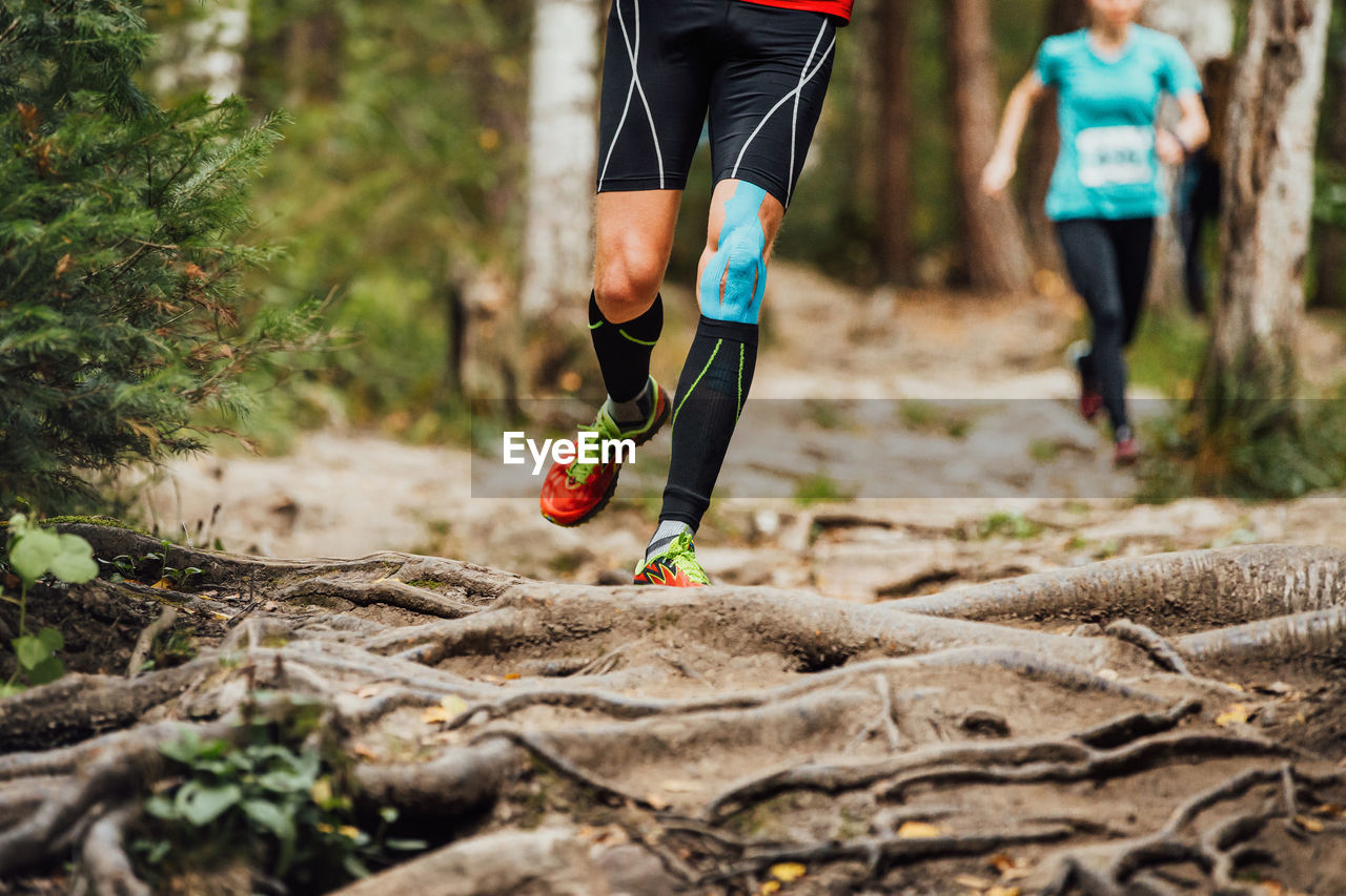 Male runner run forest race on knee kinesio tape