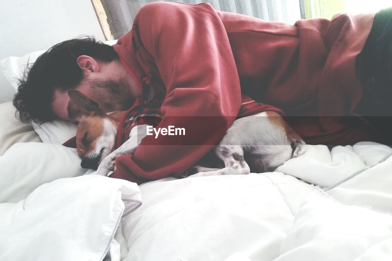 Man lying on bed at home with dog