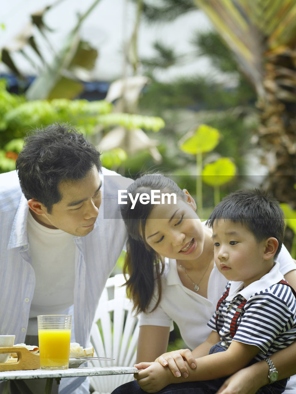 Family with breakfast on table at back yard