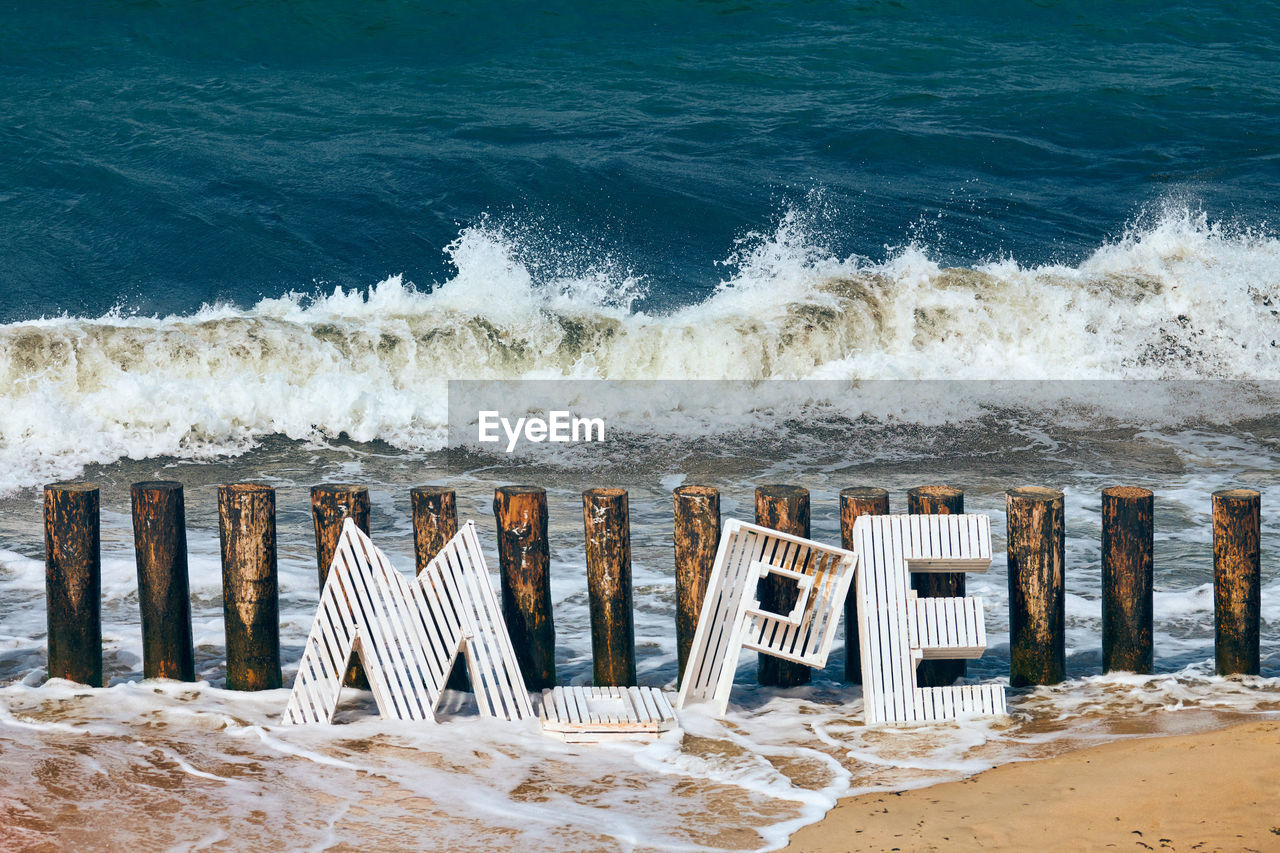 Large wooden letters forming inscription sea in russian against background of baltic sea