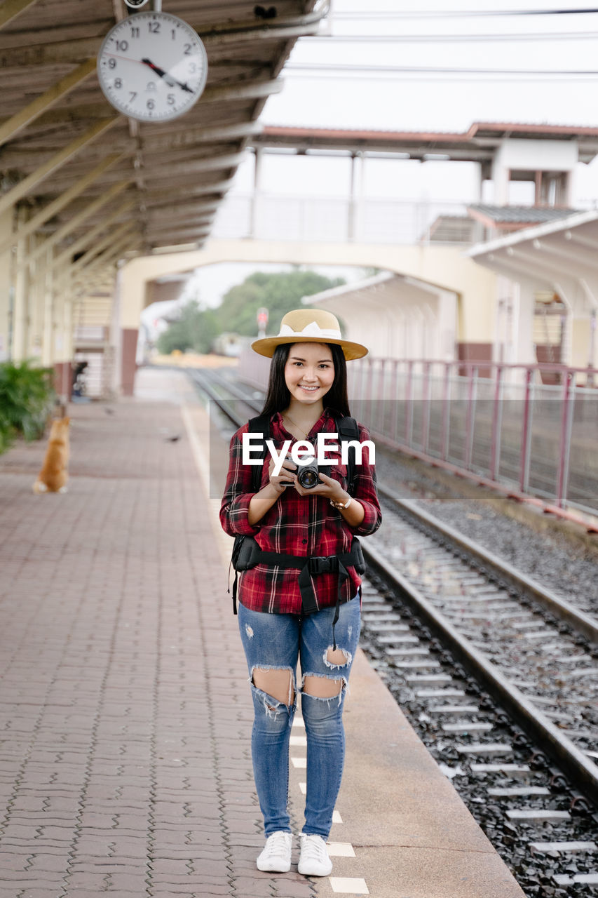 PORTRAIT OF WOMAN STANDING ON RAILROAD STATION