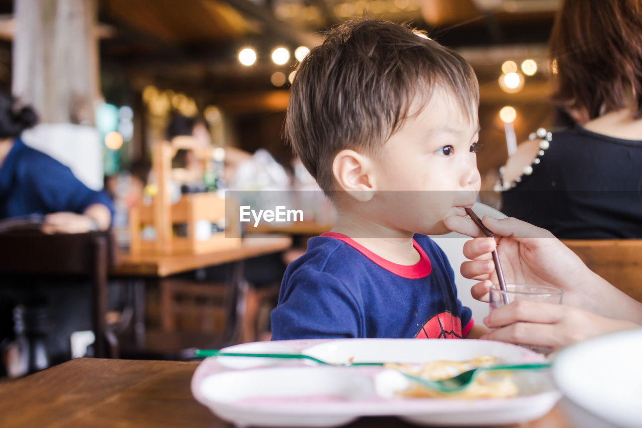 Cute baby boy having meal at restaurant