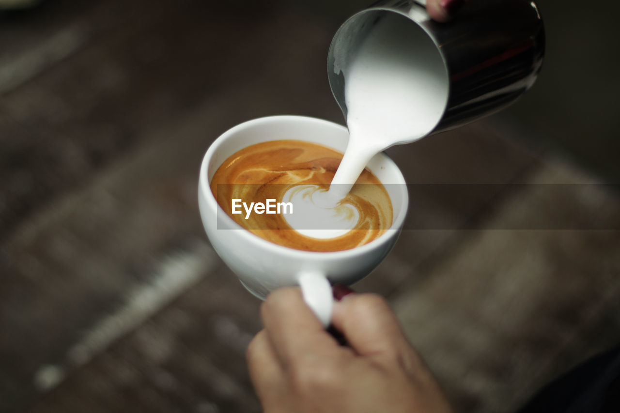 Close up shot of milk being poured into latte.