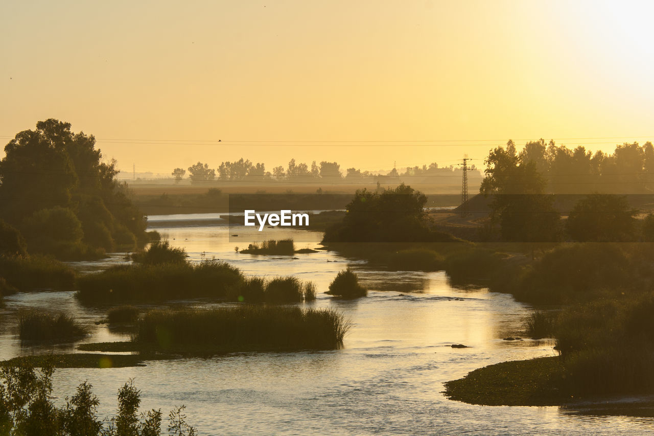 Scenic view of river against clear sky at sunset