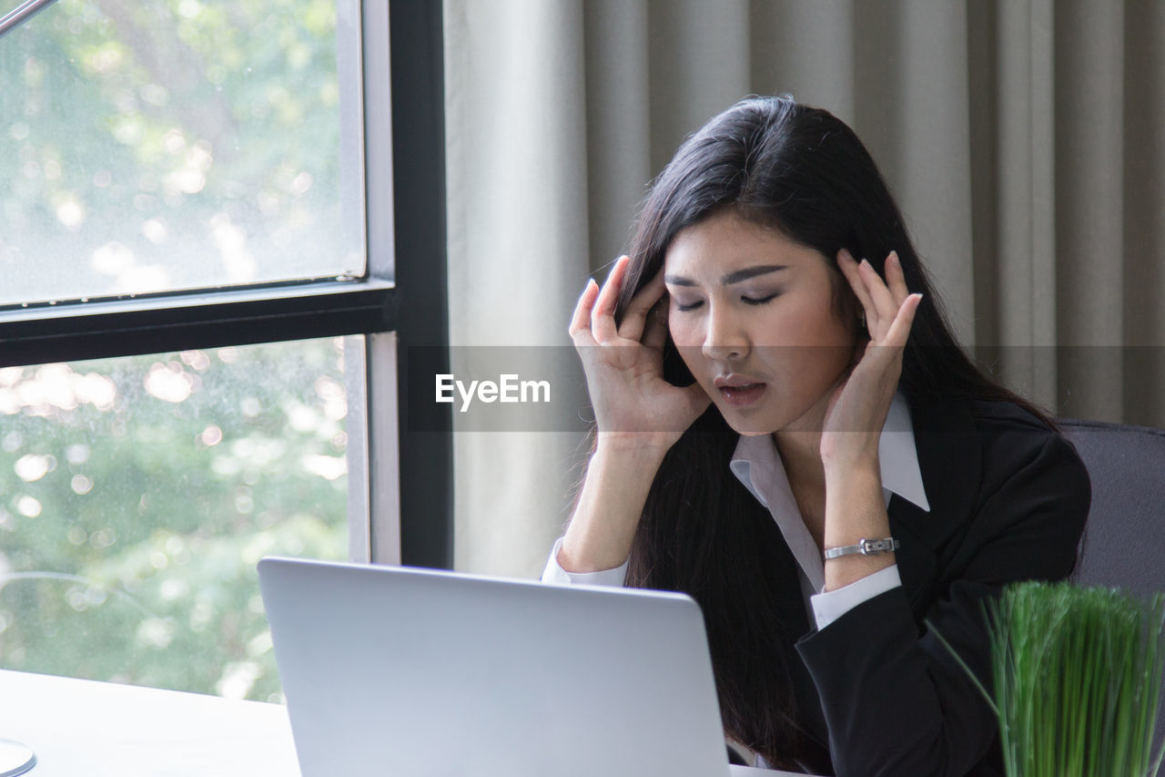 Businesswoman using laptop while working in office