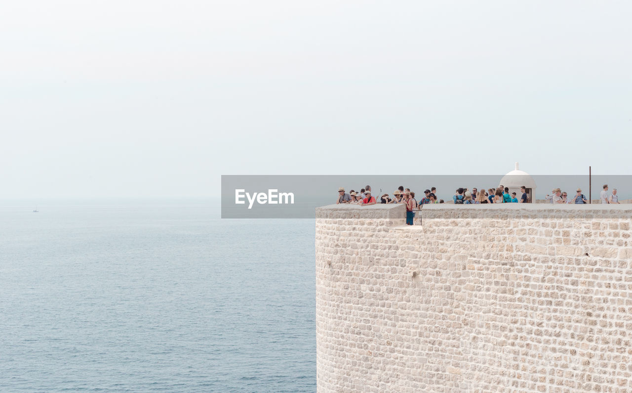 People at fort over adriatic sea against sky