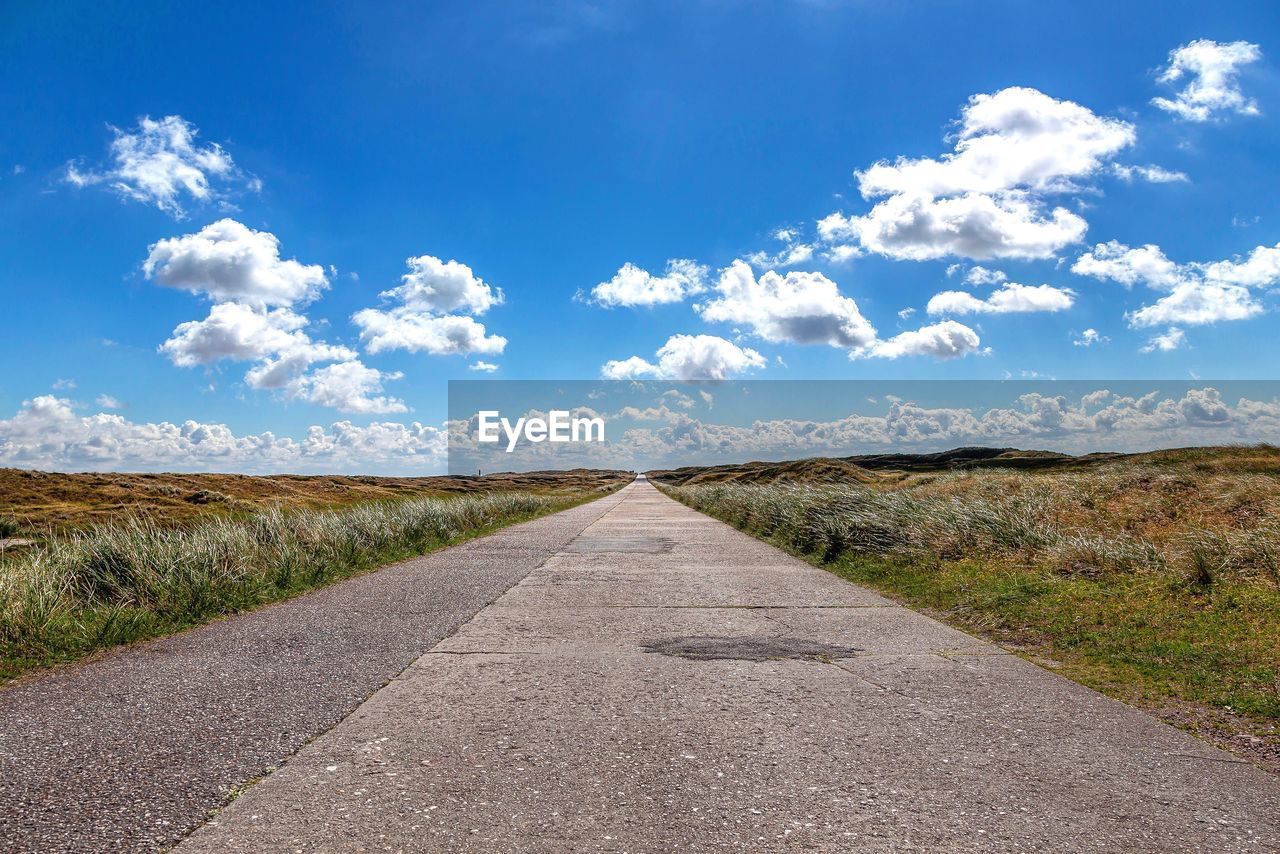 Road amidst field against sky