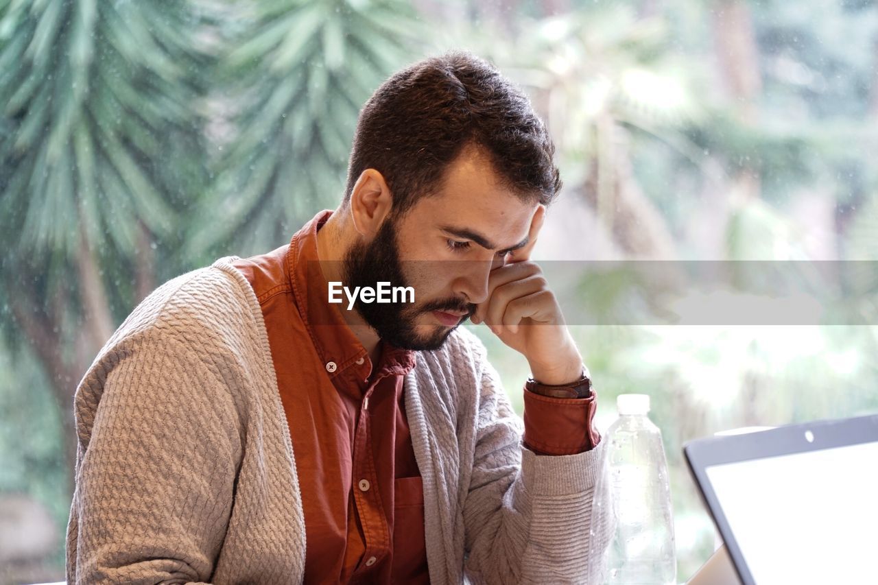 Tensed businessman looking down while sitting in office