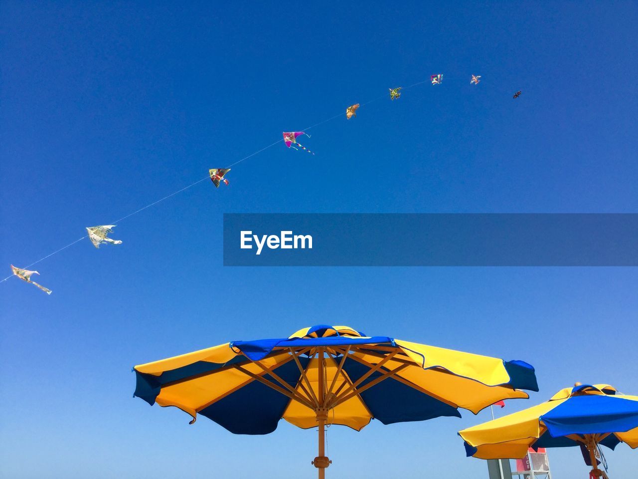 Low angle view of kites flying against clear blue sky