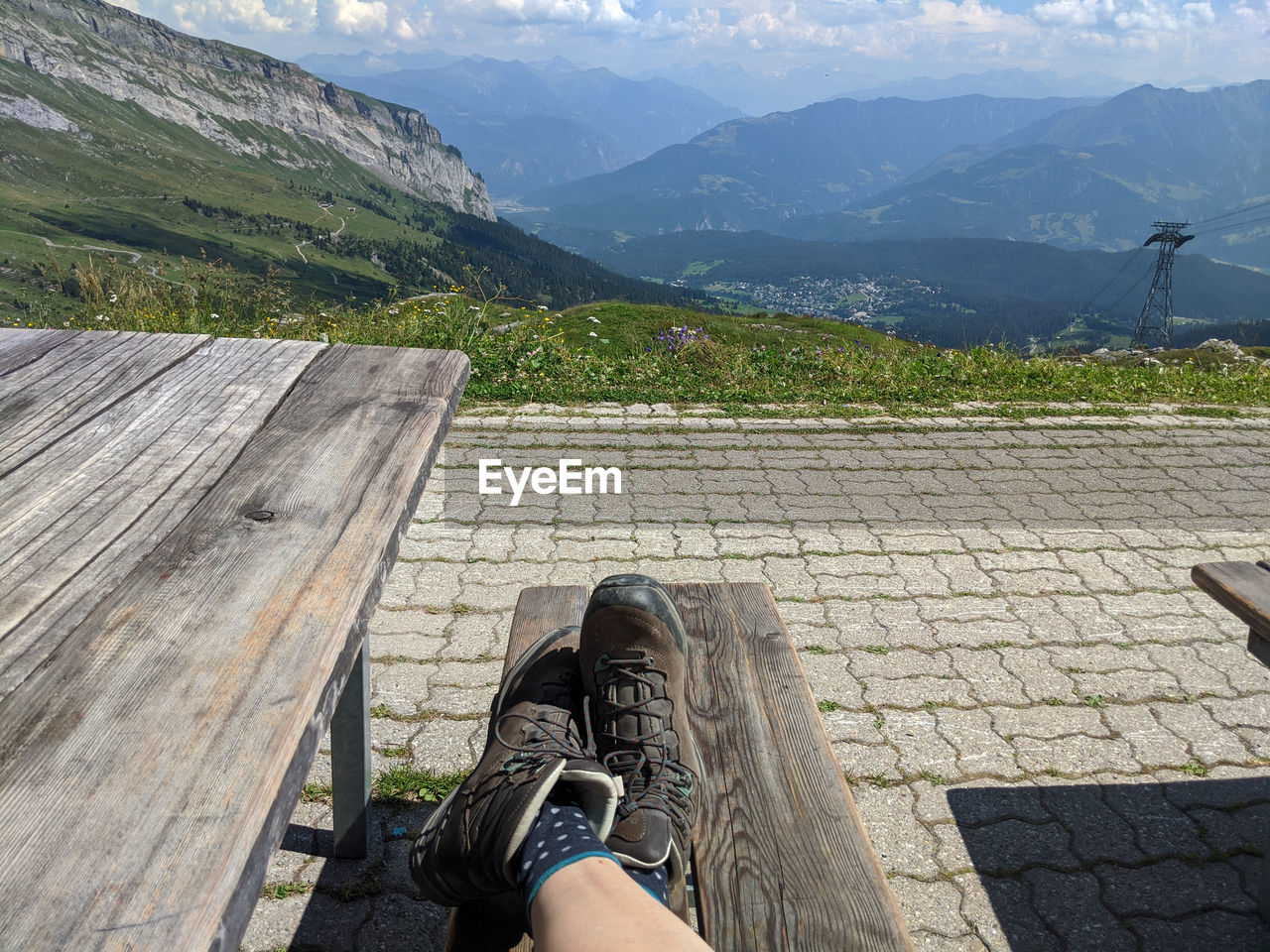 Low section of female legs wearing hiking boots relaxing on mountain