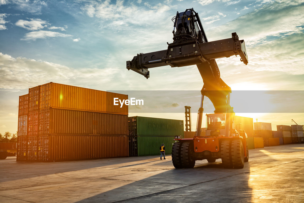 Forklift on shipping port against sky