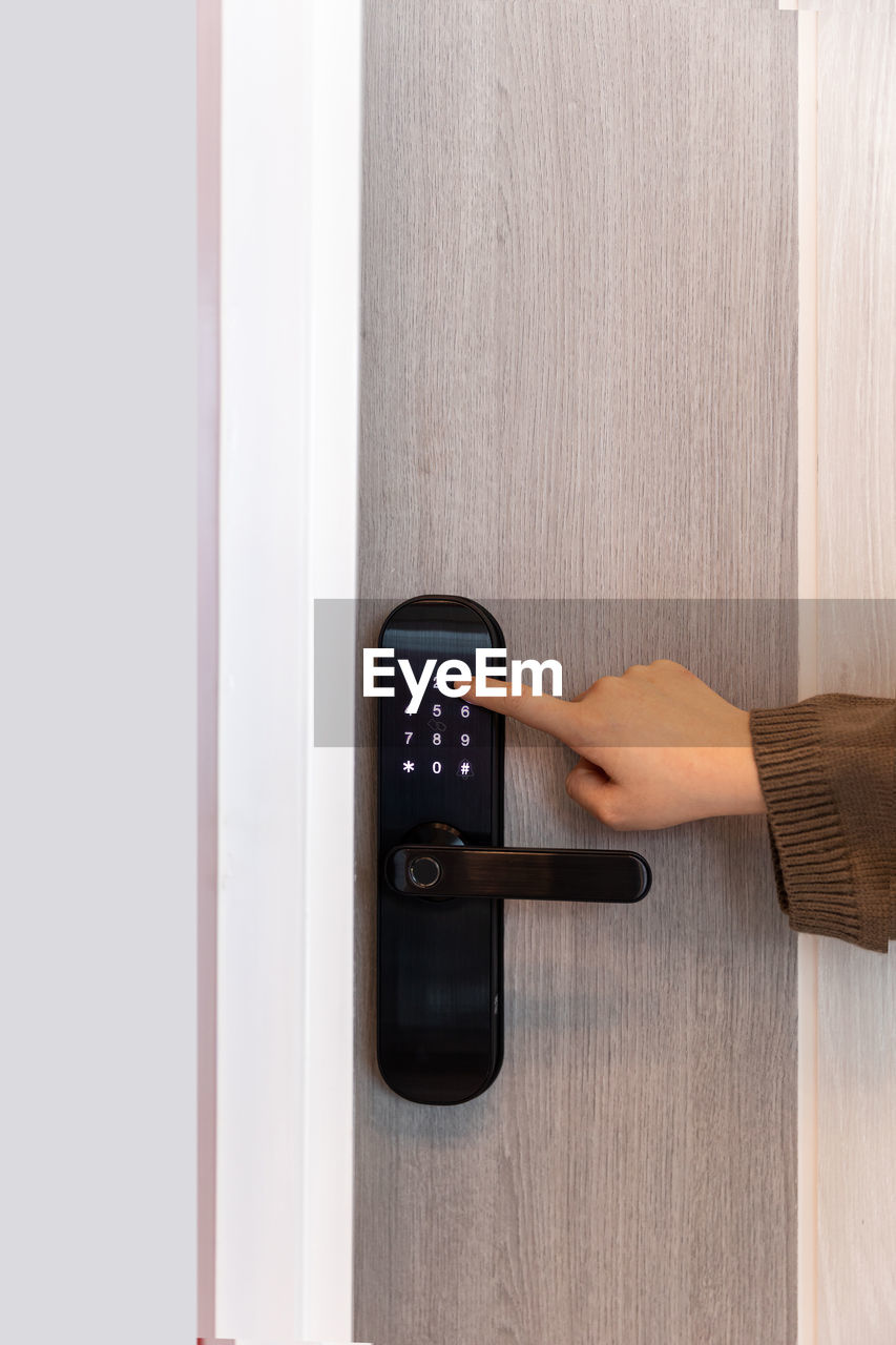 technology, hand, door, indoors, entrance, adult, one person, communication, arm, business, home interior, lifestyles, holding, push button, control, copy space, wood, office, remote control, wireless technology