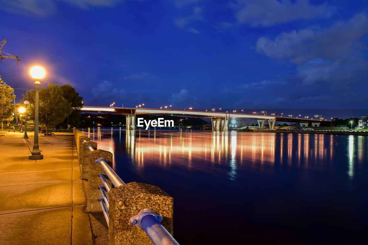 Illuminated bridge over river against sky at night