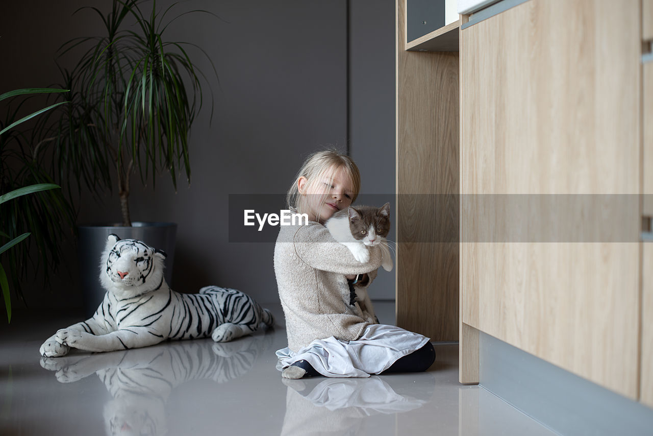 Cute girl playing with cat playing at home