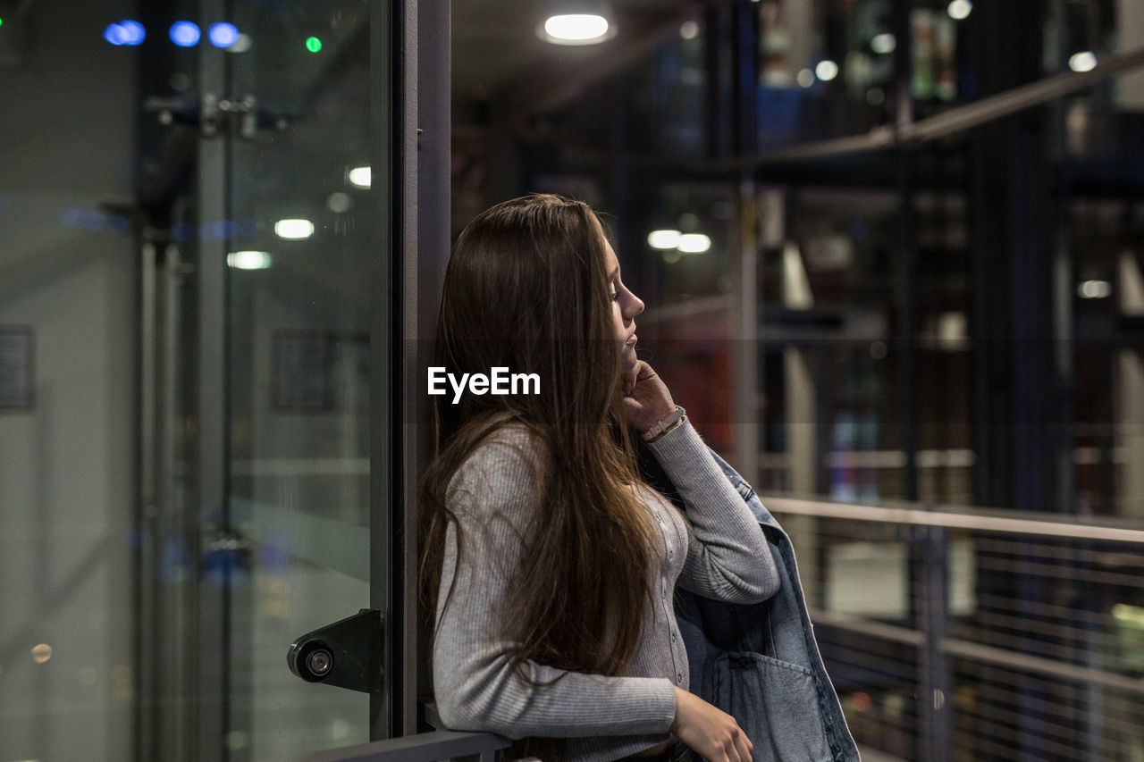 Woman looking away while standing by railing