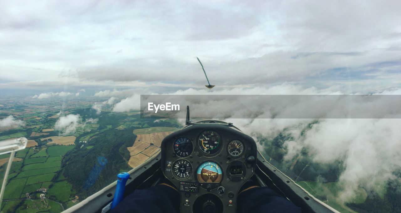 Close-up of airplane cockpit against clouds