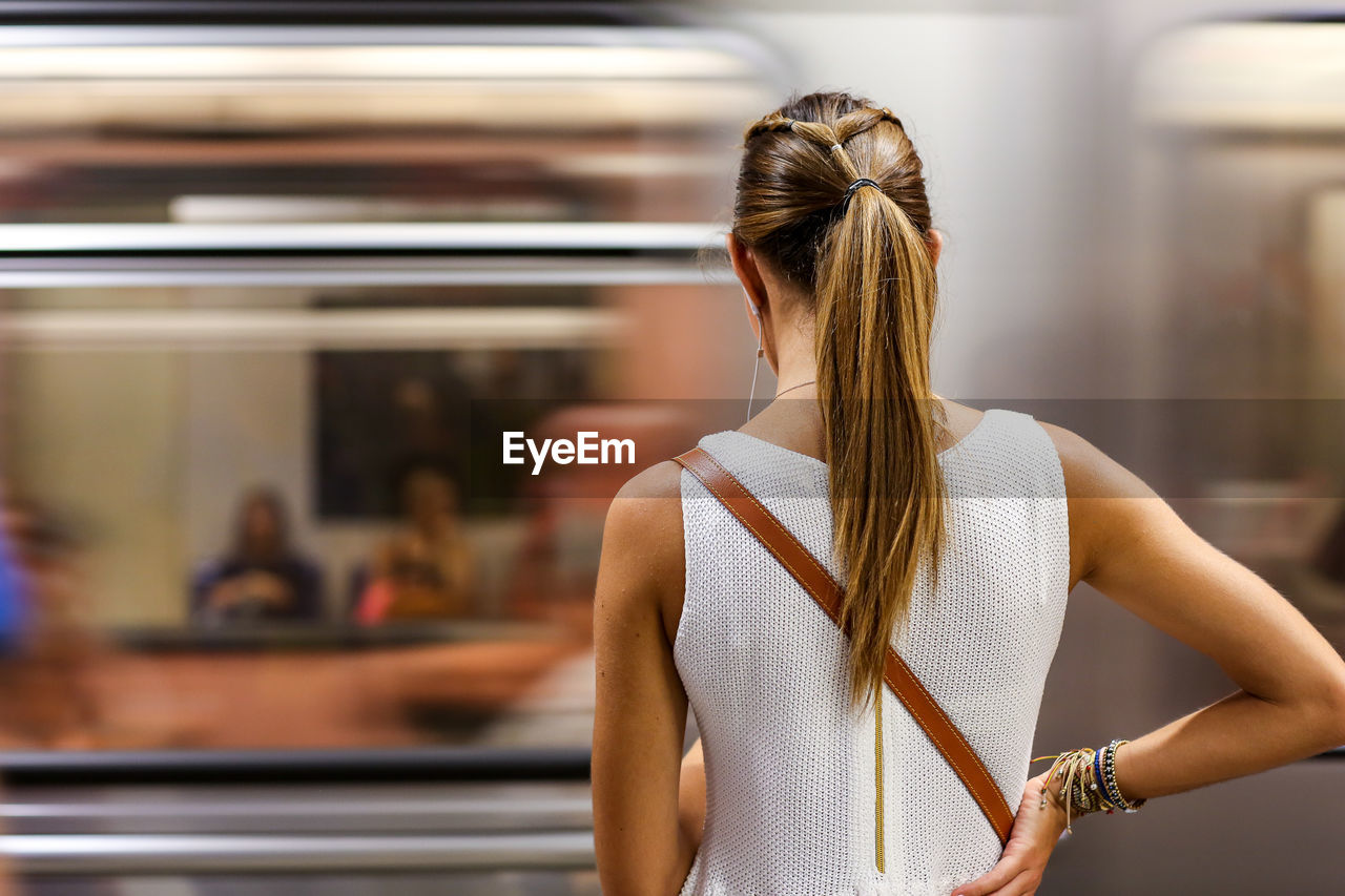 Rear view of woman standing in front of train at subway station