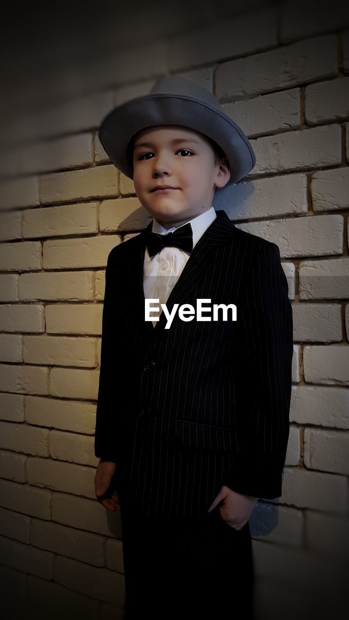 Portrait of boy standing by brick wall