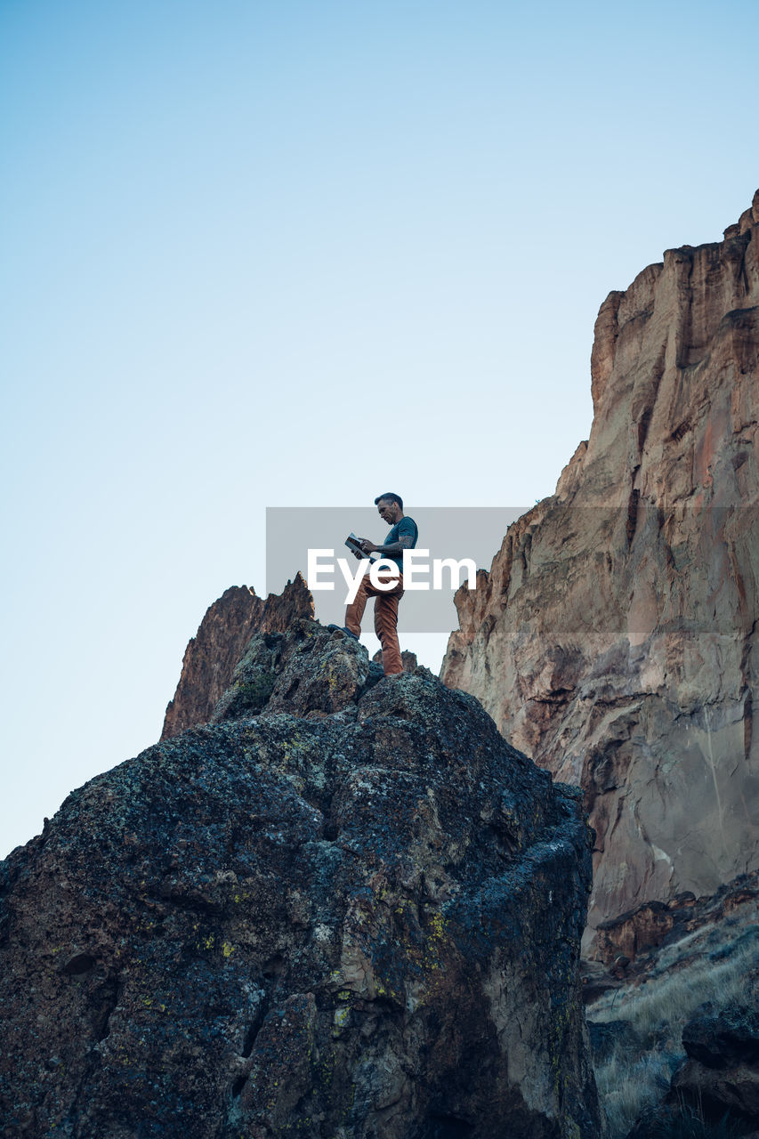 Male climber reading a guide book on the top of the boulder in oregon