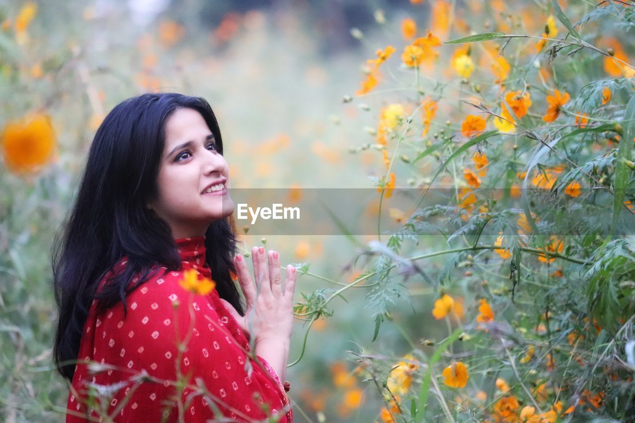 Young woman looking away while standing by tree during autumn