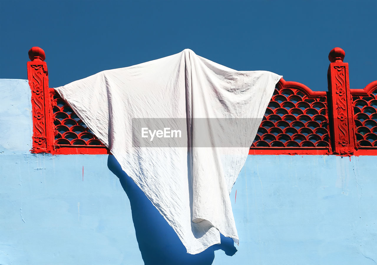 Low angle view of fabric hanging from red railing at building terrace