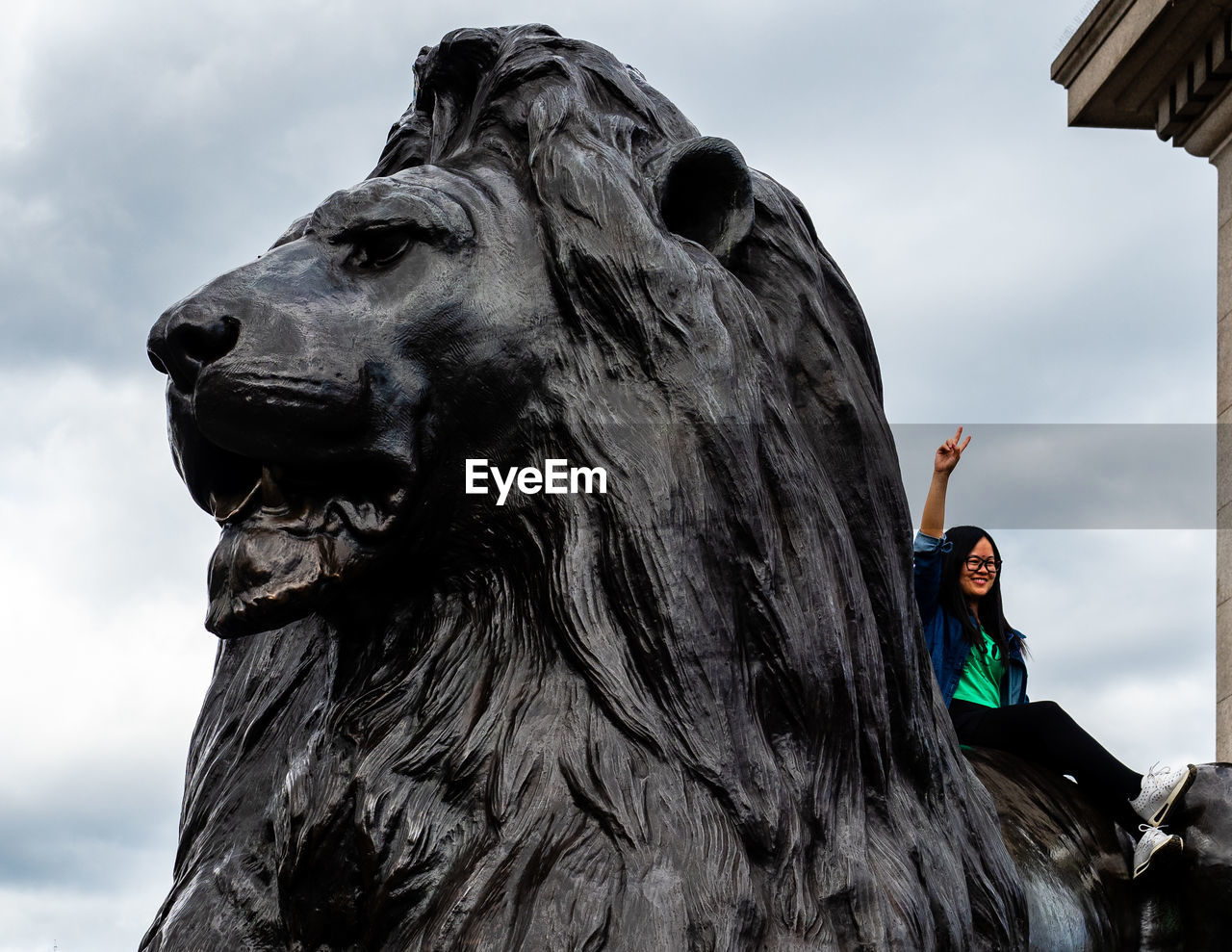 Tourist woman on lion statue in london