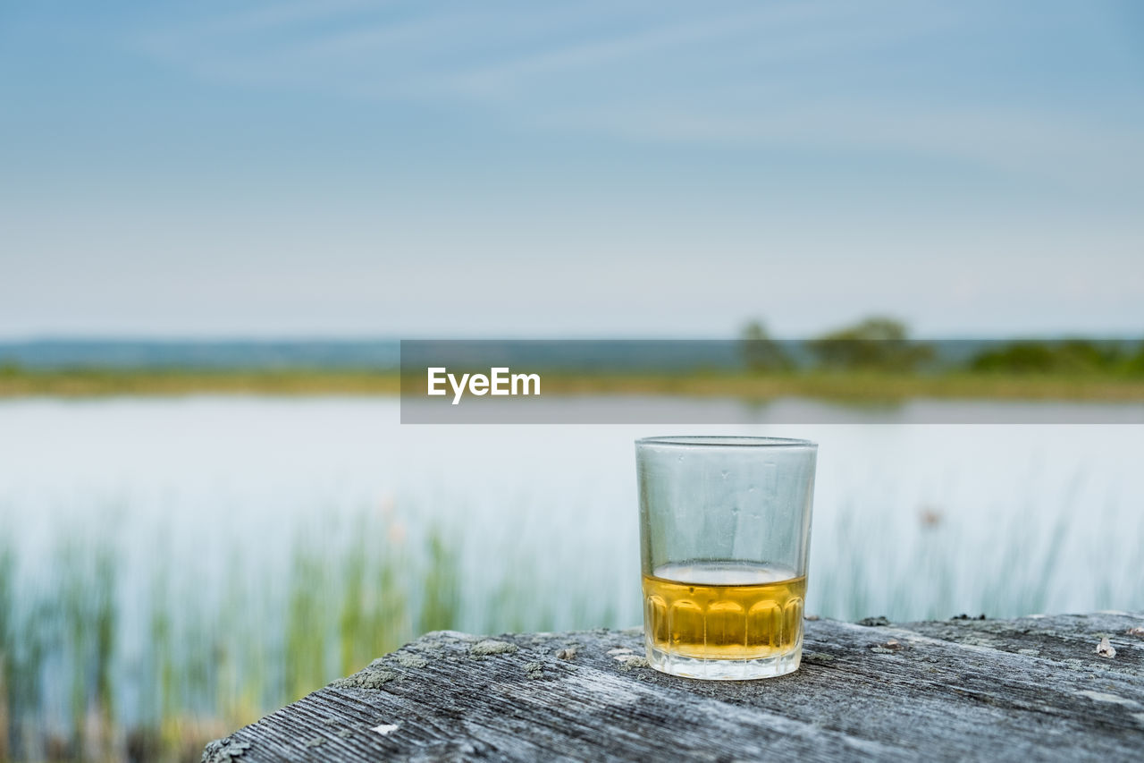 DRINK ON TABLE AGAINST LAKE