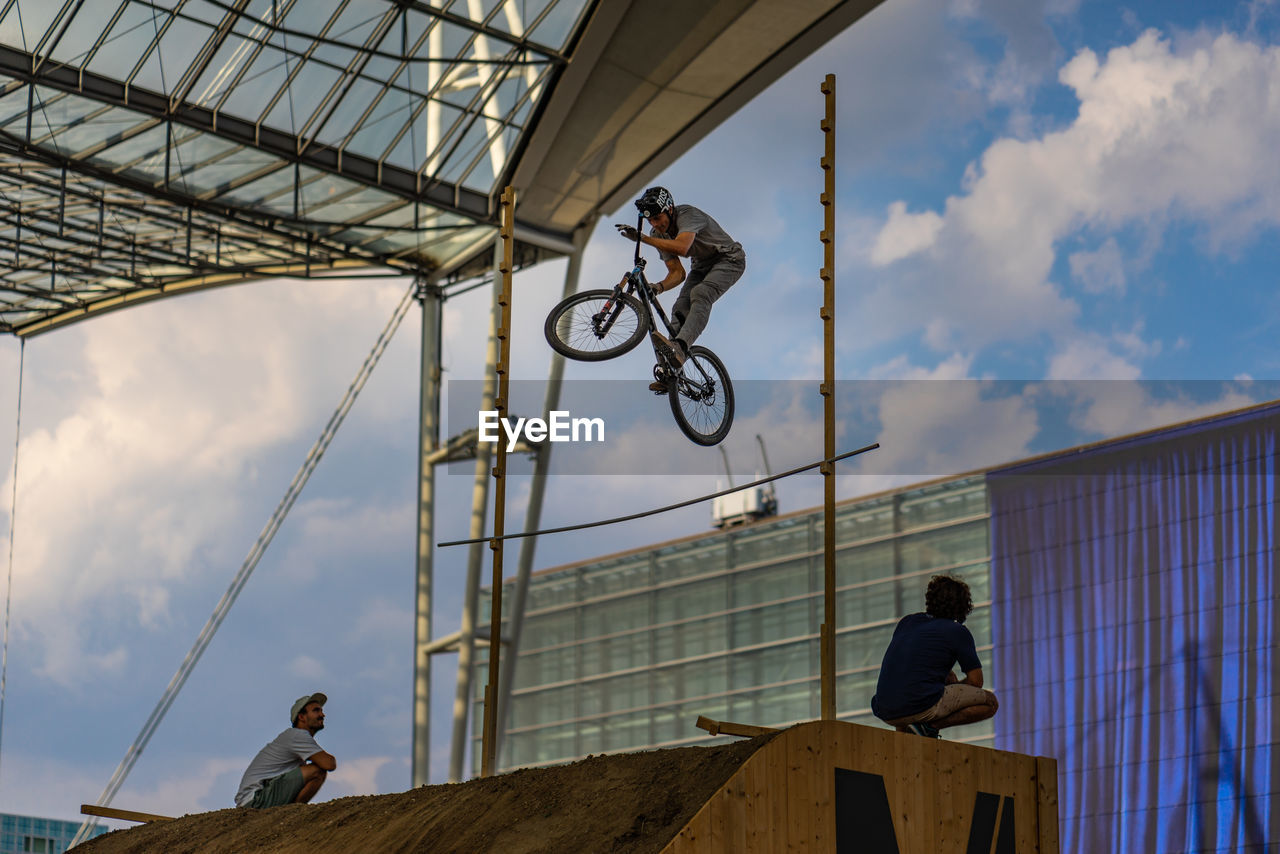 LOW ANGLE VIEW OF MEN WITH BICYCLE ON POLE