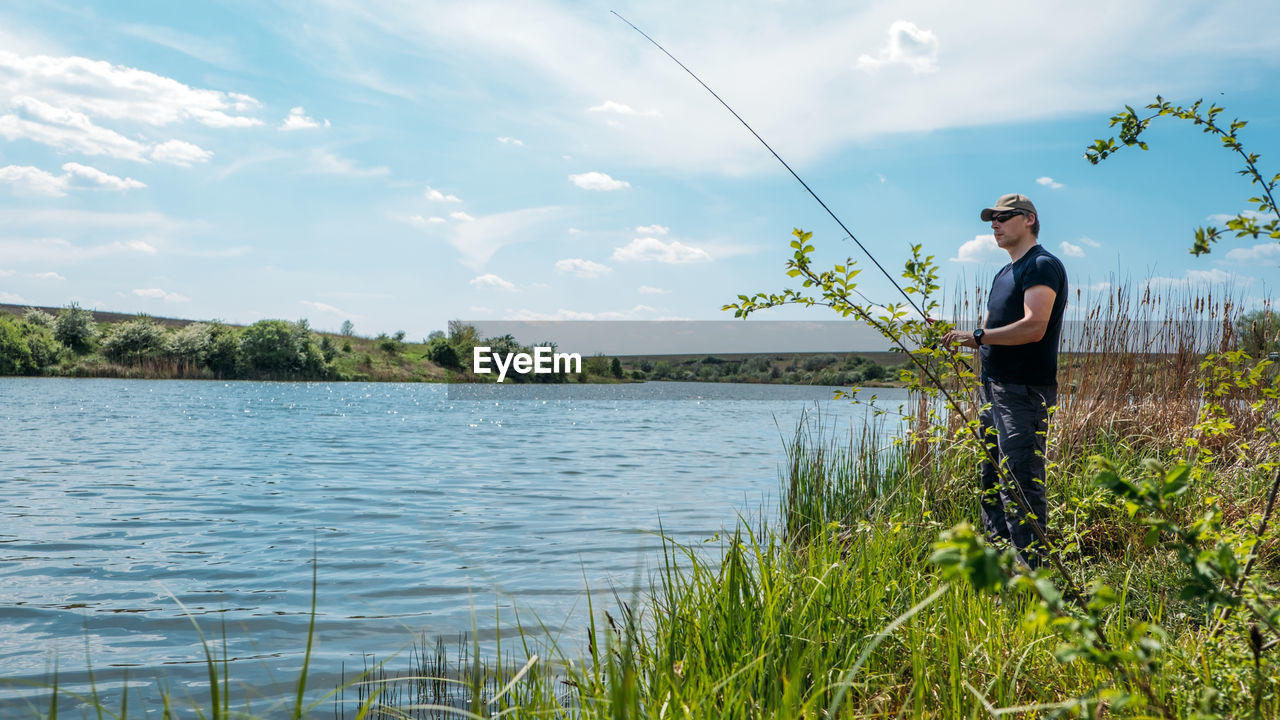 Fisherman with spinning rod on nature background. angler man with fishing spinning or casting rod