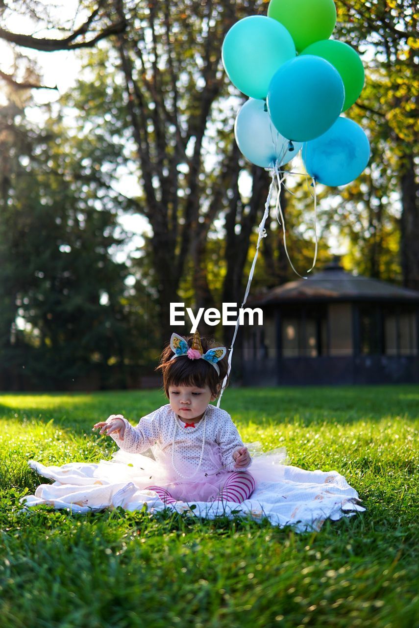 Cute girl with balloons sitting in park