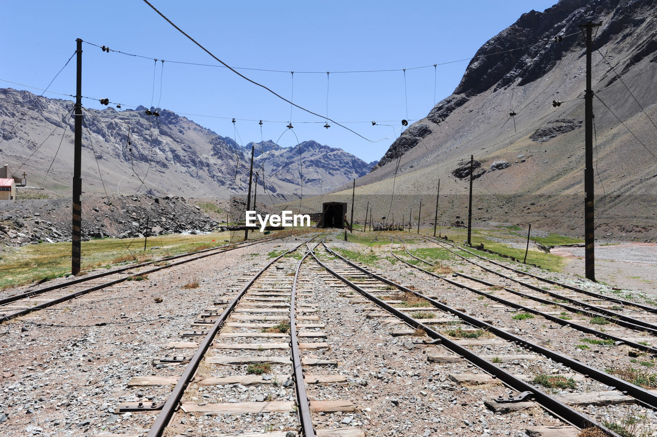 Railroad track by mountains against clear sky