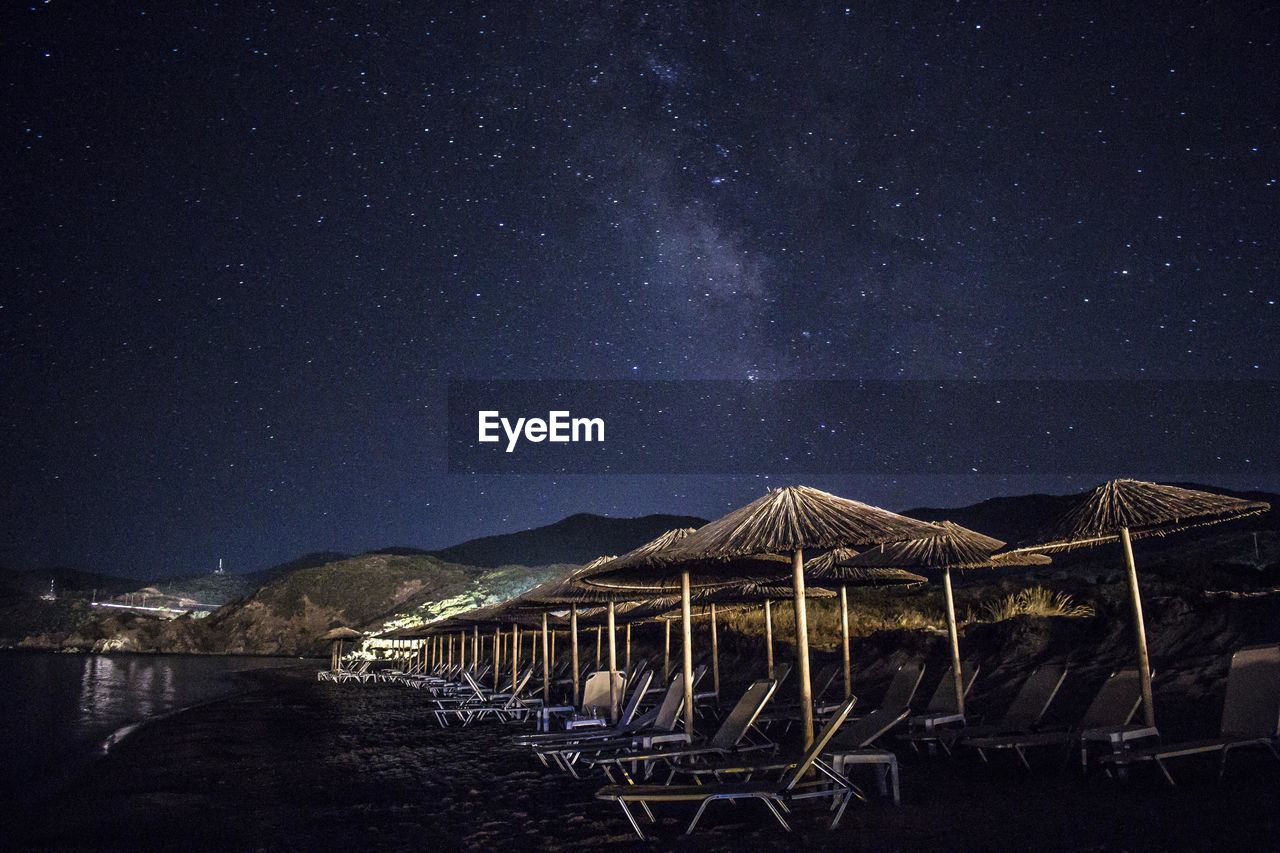 Thatched roofs and lounge chairs at beach at night