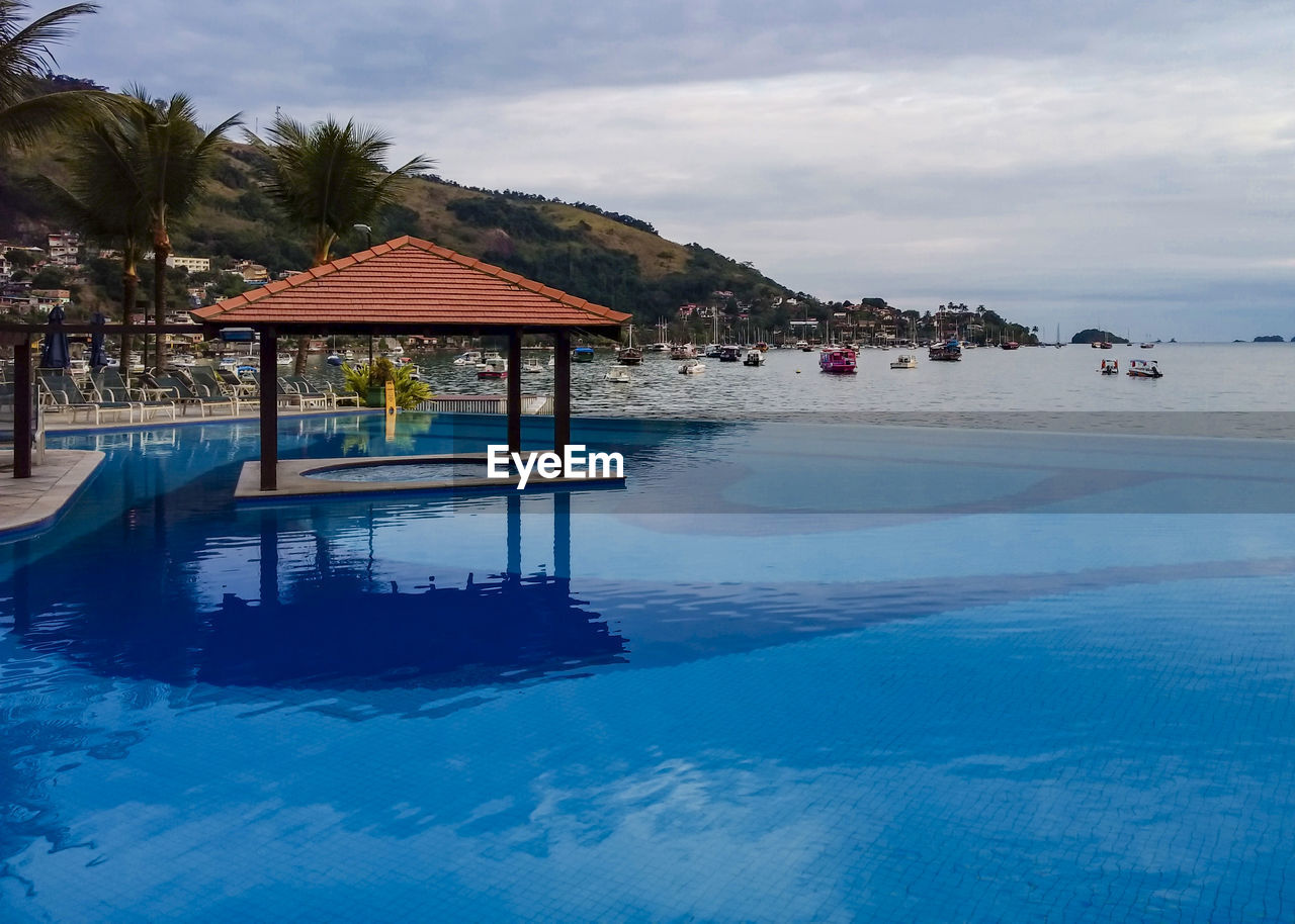 View of swimming pool by sea against sky