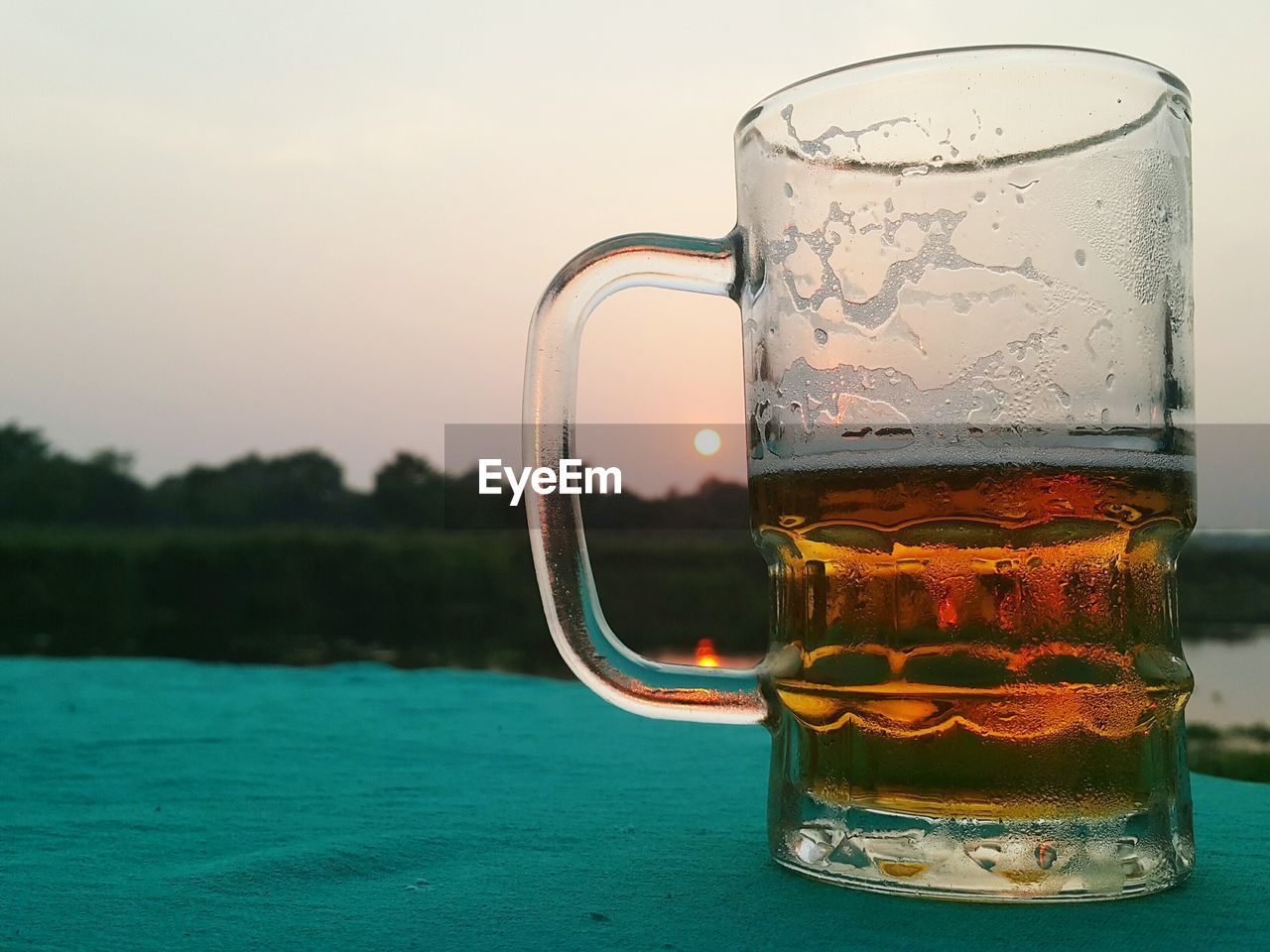 Close-up of beer glass against water