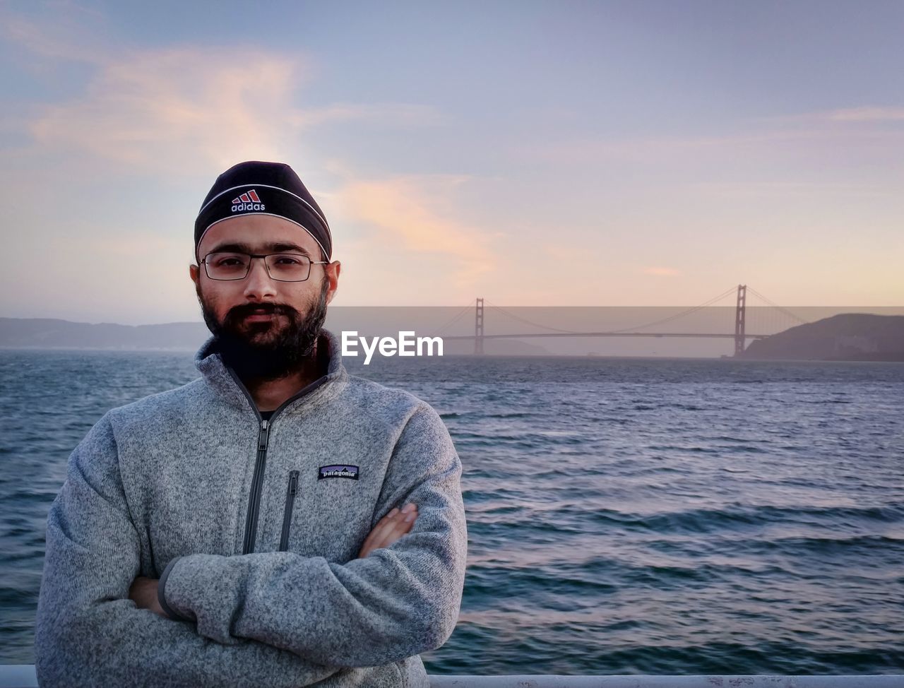 PORTRAIT OF YOUNG MAN STANDING AGAINST SEA