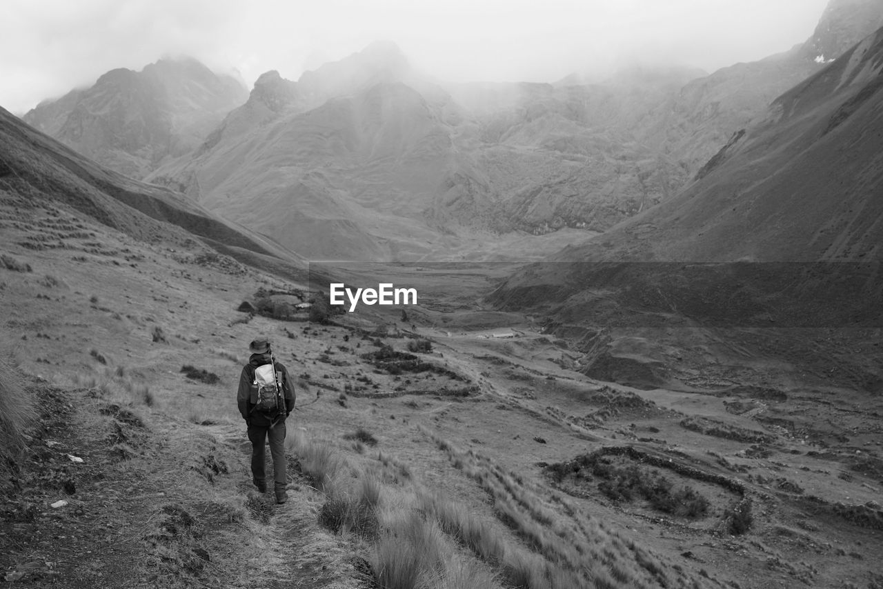 Rear view of woman walking on mountain against sky