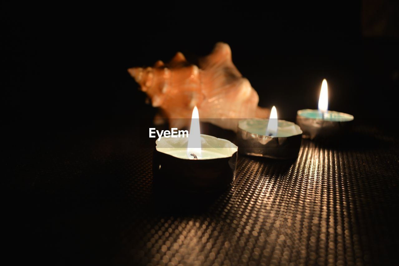 Close-up of lit candles on table at night