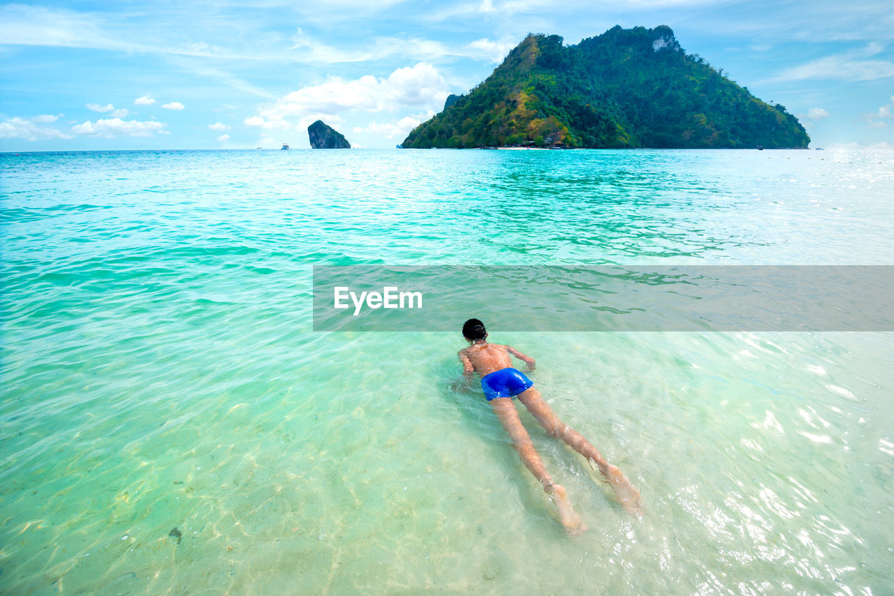 Rear view of boy in sea against sky