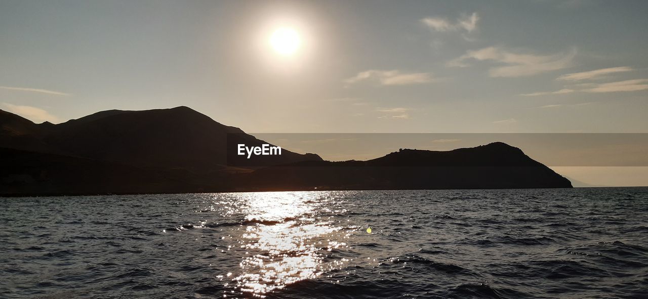 SCENIC VIEW OF SEA AND SILHOUETTE MOUNTAINS AGAINST SKY