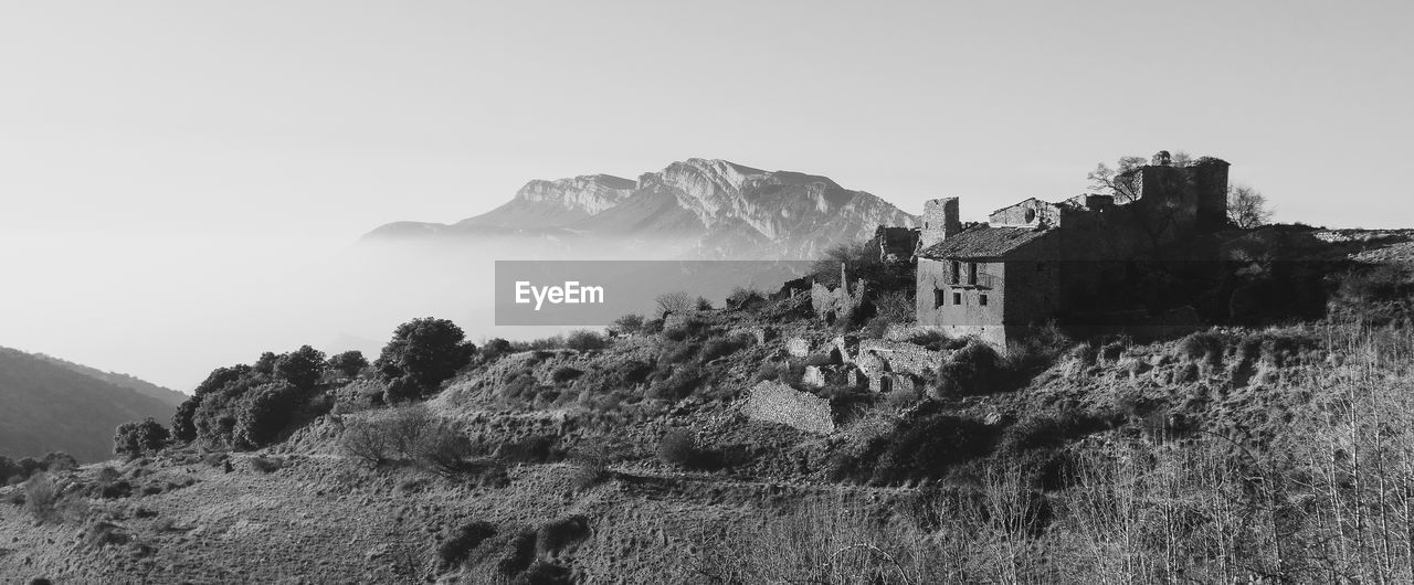 mountain, sky, black and white, rock, environment, nature, landscape, scenics - nature, monochrome photography, monochrome, land, architecture, travel, travel destinations, no people, history, beauty in nature, mountain range, built structure, building, outdoors, panoramic, the past, plant, terrain, tourism, clear sky, tranquility, building exterior, tree, day, cliff, non-urban scene, tranquil scene, house