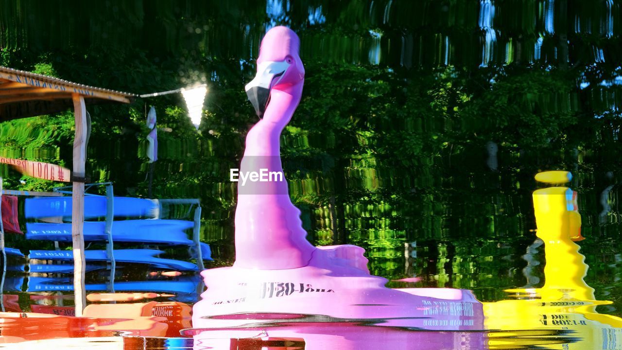 MIDSECTION OF WOMAN WITH PINK UMBRELLA ON RAILING AGAINST ILLUMINATED WALL