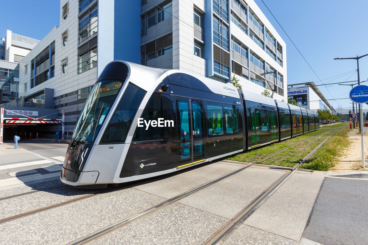 TRAIN ON RAILROAD TRACK BY BUILDINGS IN CITY