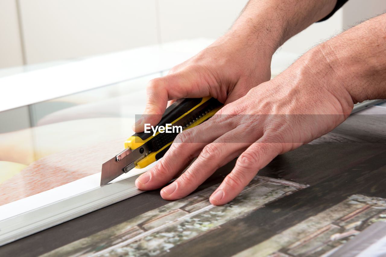 Cropped image of man using utility knife on table