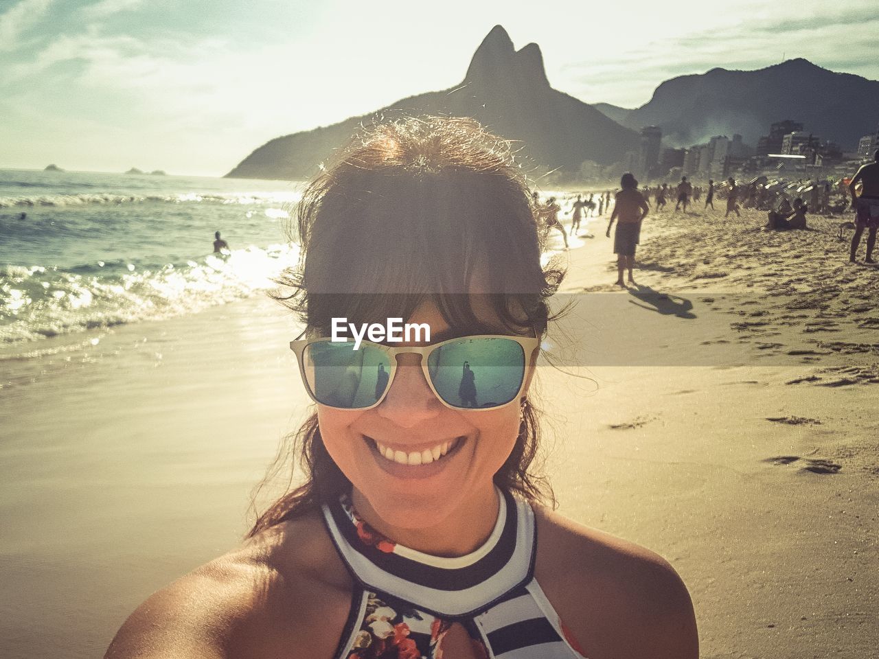 Portrait of woman smiling while wearing sunglasses at beach