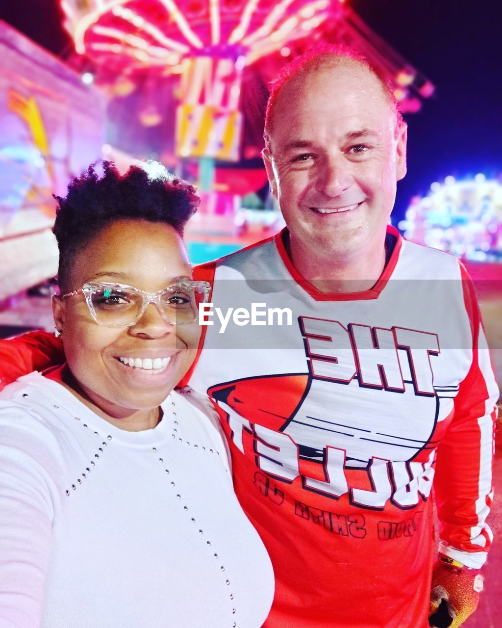 smiling, happiness, emotion, two people, adult, portrait, looking at camera, men, cheerful, togetherness, positive emotion, young adult, sports, waist up, event, celebration, women, red, enjoyment, night, love, clothing