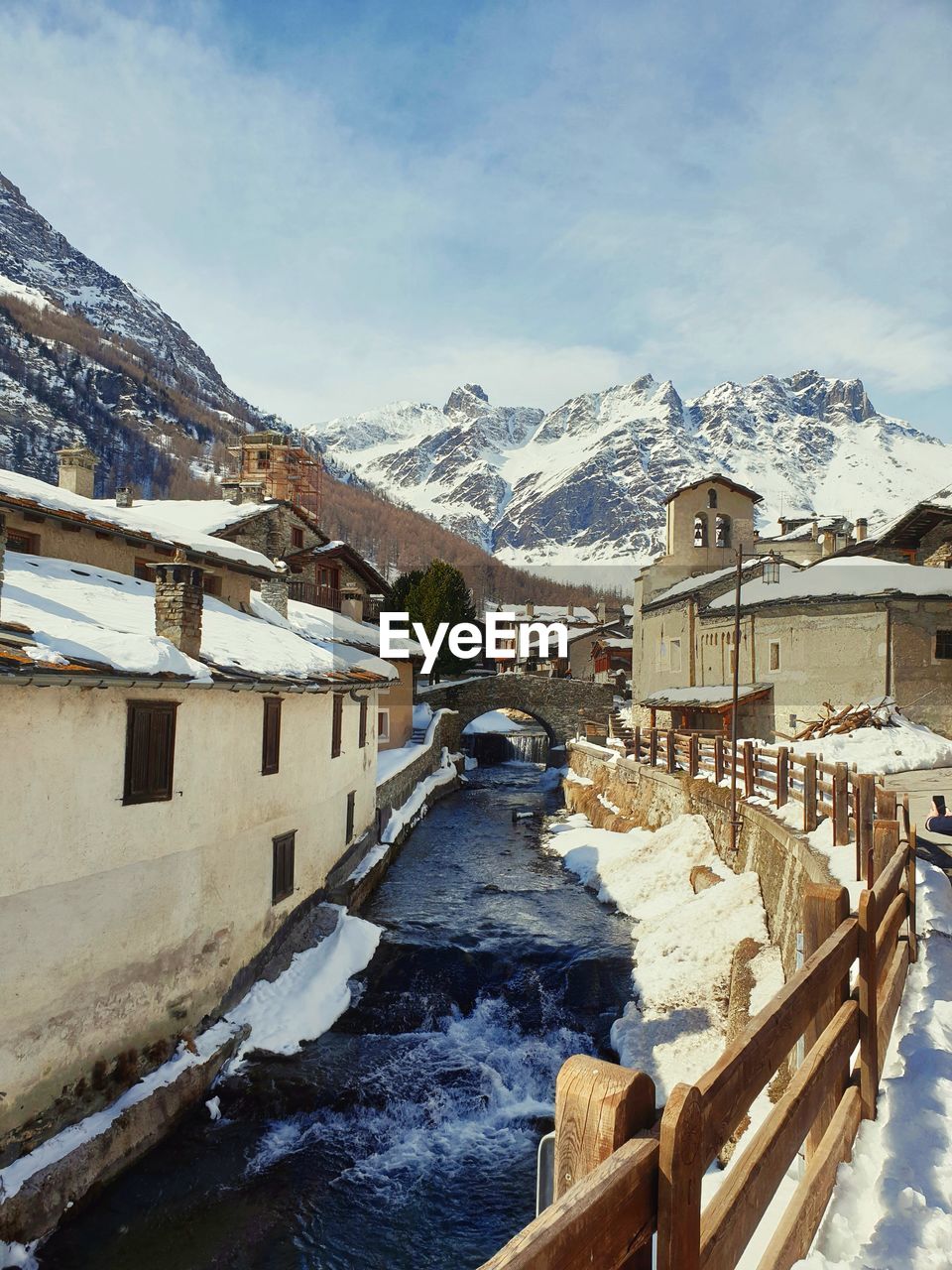 SNOW COVERED BUILDINGS BY MOUNTAINS AGAINST SKY